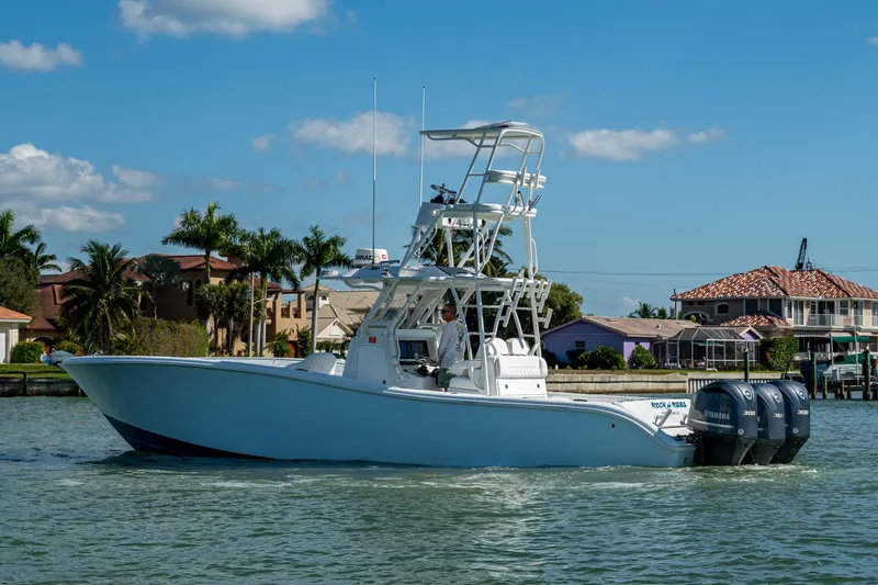 Rock N Reel Yacht Photos Pics 2018 Yellowfin 36 Offshore boat cruising near waterfront homes under blue sky.