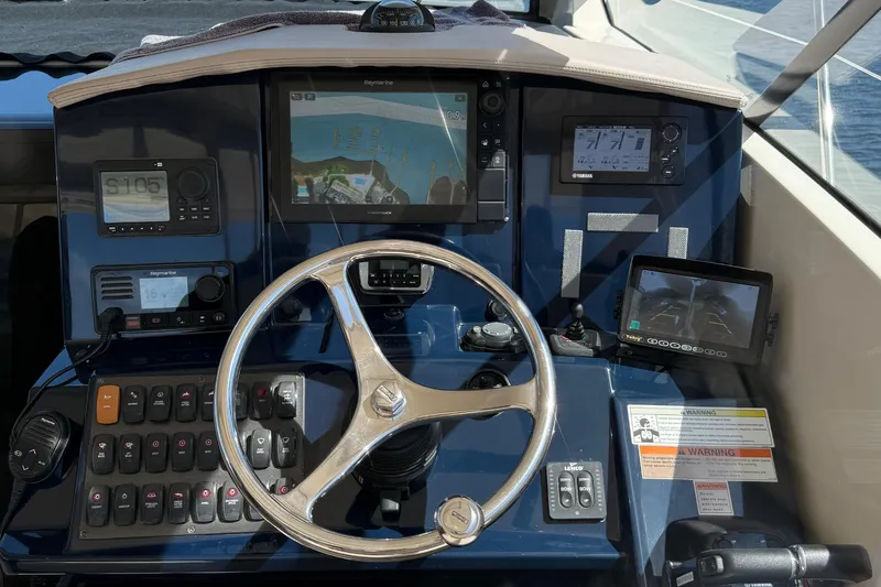  Yacht Photos Pics Control panel of 2013 Pursuit SC 365i Sport Coupe with navigation screens and steering wheel.