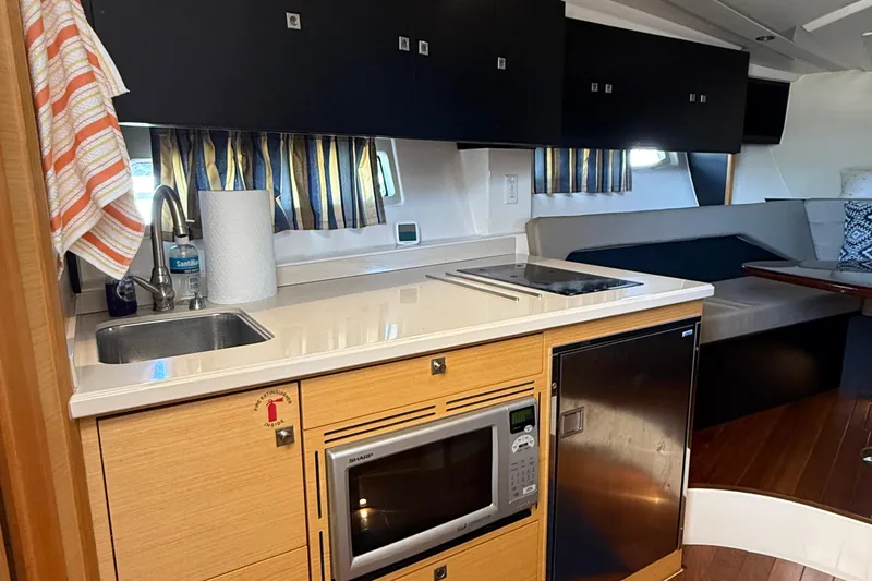  Yacht Photos Pics 2013 Pursuit SC 365i Sport Coupe interior kitchen with sink, microwave, and seating area.