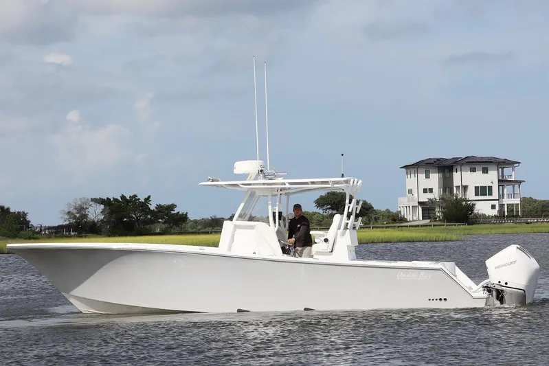 Yacht Photos Pics 2022 Onslow Bay 33 boat cruising on a calm waterway near a modern house.