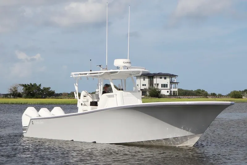  Yacht Photos Pics 2022 Onslow Bay 33 boat cruising on a calm waterway near a modern house.
