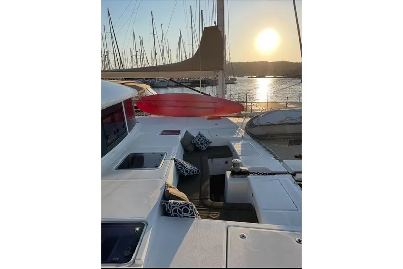 Somni Yacht Photos Pics Lagoon 560 S2 yacht deck at sunset, featuring cushions and a serene marina view.