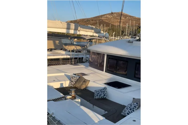 Somni Yacht Photos Pics 2013 Lagoon 560 S2 yacht with cushioned deck seating and scenic marina backdrop.