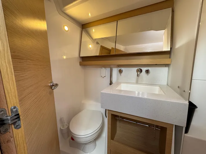 Pura Vida Yacht Photos Pics Modern bathroom in 2022 Dufour 530 yacht, featuring sleek sink, mirror, and toilet.