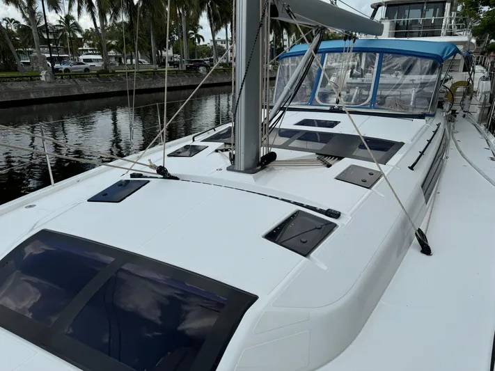 Pura Vida Yacht Photos Pics Dufour 530 sailboat deck, 2022 model, docked by palm trees and calm water.