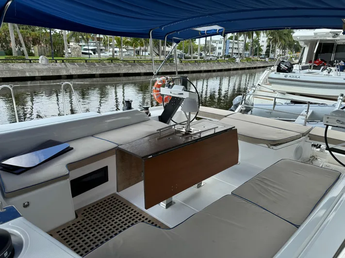 Pura Vida Yacht Photos Pics Dufour 530 yacht cockpit with seating, table, and canopy, docked by a canal.