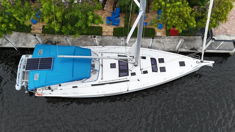 Pura Vida Yacht Photos Pics Aerial view of 2022 Dufour 530 sailboat docked by a lush, green waterfront.