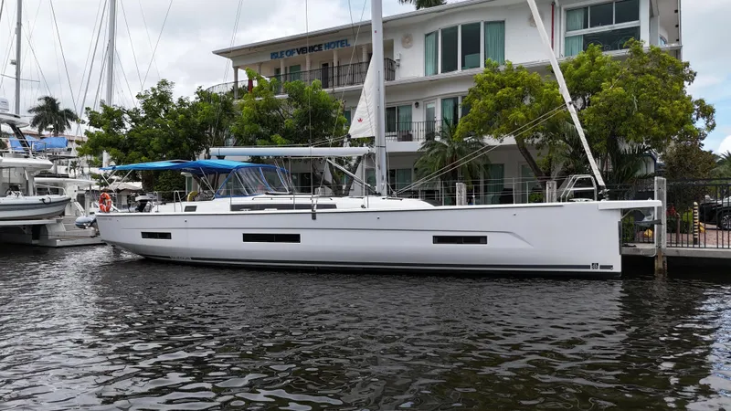Pura Vida Yacht Photos Pics 2022 Dufour 530 sailboat docked near a waterfront hotel.