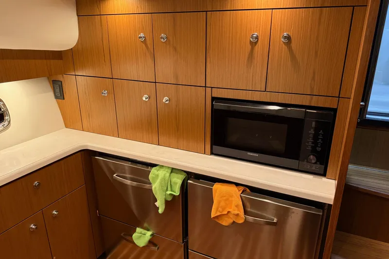  Yacht Photos Pics 2023 Tiara Yachts 43 Open kitchen with wood cabinets, microwave, and stainless steel appliances.