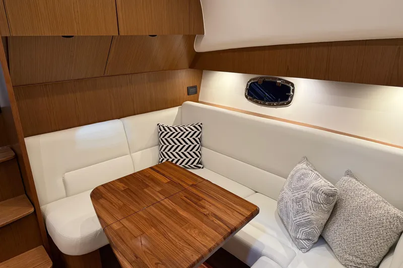  Yacht Photos Pics 2023 Tiara Yachts 43 Open interior with white seating, wooden table, and decorative pillows.