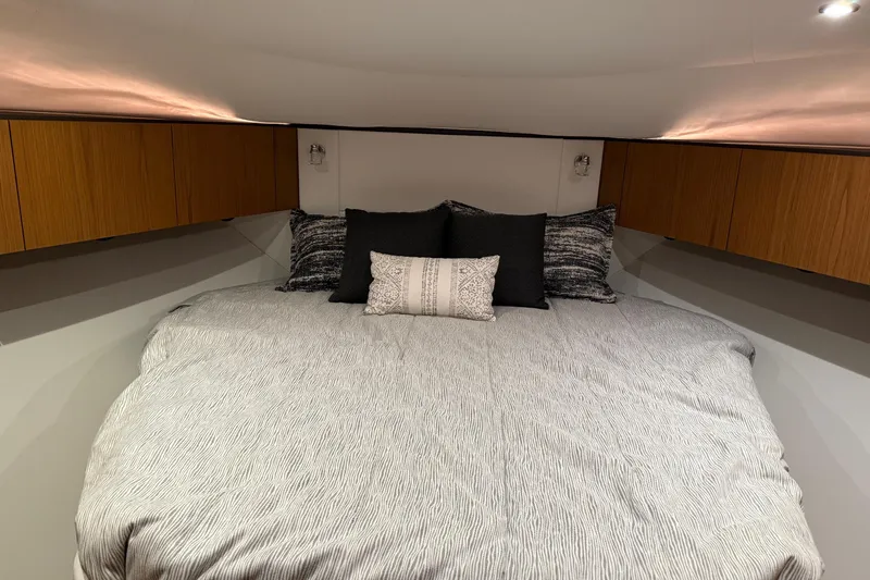  Yacht Photos Pics Luxurious bedroom interior of 2023 Tiara Yachts 43 Open, featuring elegant bedding and wood cabinetry.