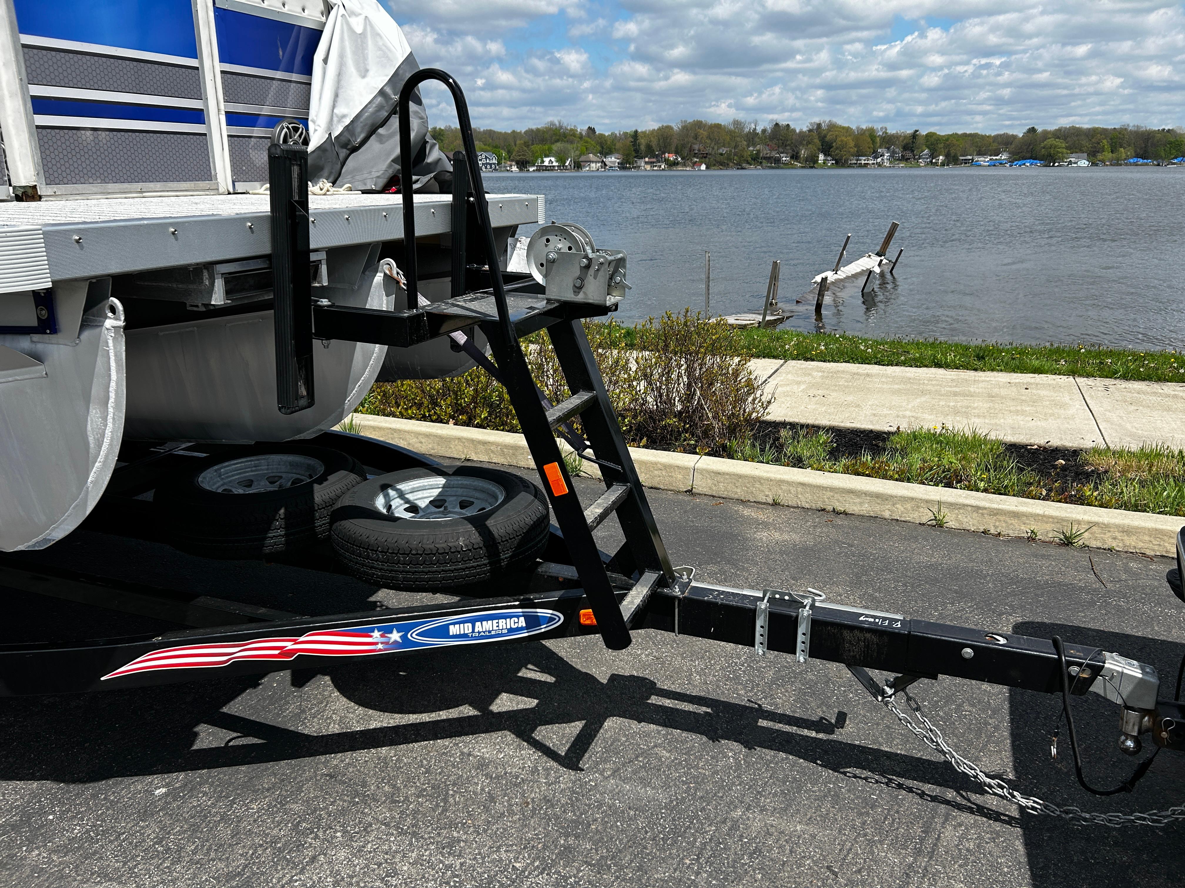 Trailer hitch and ladder of a 2005 Evolution 26 boat by a lakeside.