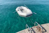 Inflatable dinghy tied to a Nimbus 365 yacht, floating on clear turquoise water.