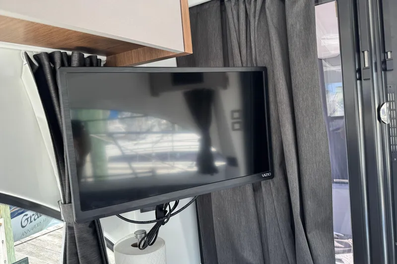  Yacht Photos Pics Flat-screen TV inside 2024 Beneteau Antares 11 boat, surrounded by dark curtains.