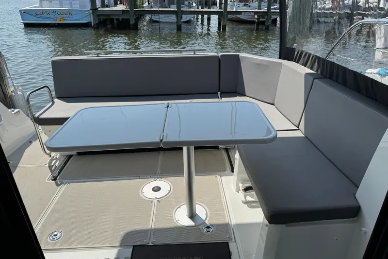  Yacht Photos Pics 2024 Beneteau Antares 11 boat interior with seating and table, docked by the water.