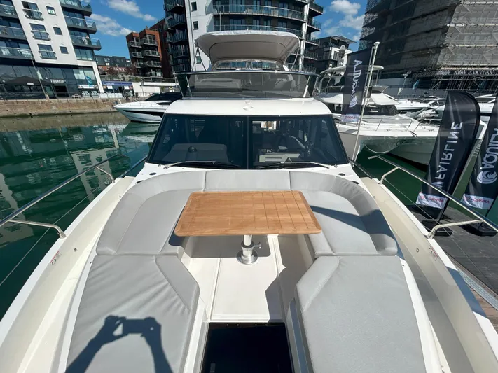 In Stock Yacht Photos Pics 2025 Absolute 47 Fly yacht with spacious deck and table, docked in a modern marina.