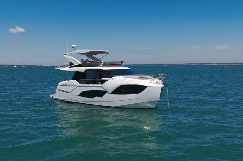 In Stock Yacht Photos Pics Luxury Absolute 47 Fly yacht, 2025 model, cruising on serene blue waters under a clear sky.