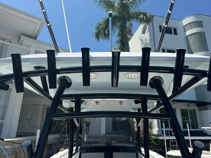  Yacht Photos Pics 2022 Sea Fox 328 Commander boat with rod holders and T-top, docked near a modern building.