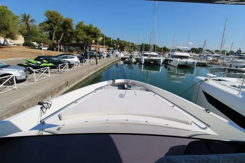 L Yacht Photos Pics 2023 MandaYachts Manda S05 docked in a marina, surrounded by other boats and parked cars.