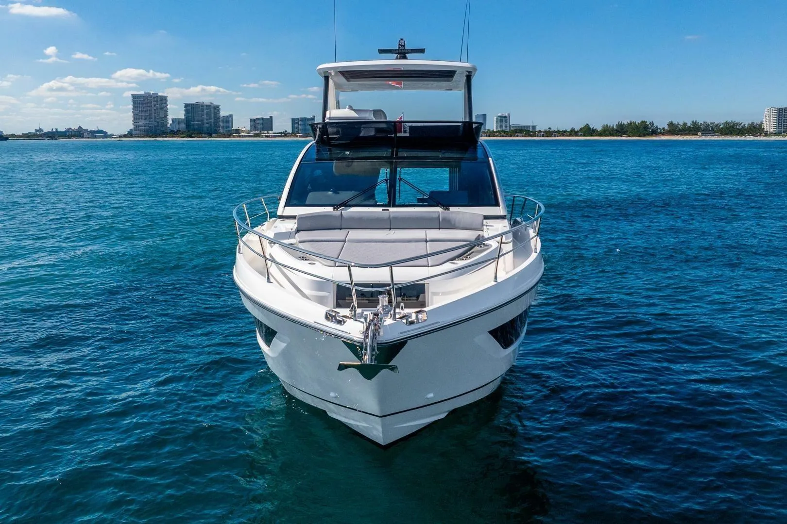 Front view of 2025 Pearl 63 yacht on blue ocean with city skyline.