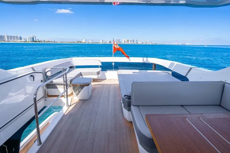  Yacht Photos Pics Luxurious Pearl 63 yacht deck with ocean view, 2025 model, featuring modern seating and city skyline.