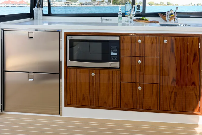 In Stock Yacht Photos Pics Modern kitchen area on 2026 MJM 47X yacht with microwave and stainless steel fridge.