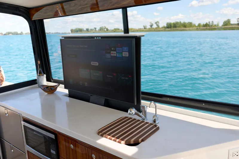 In Stock Yacht Photos Pics Luxury interior of 2026 MJM 47X yacht with TV and kitchenette by the water.