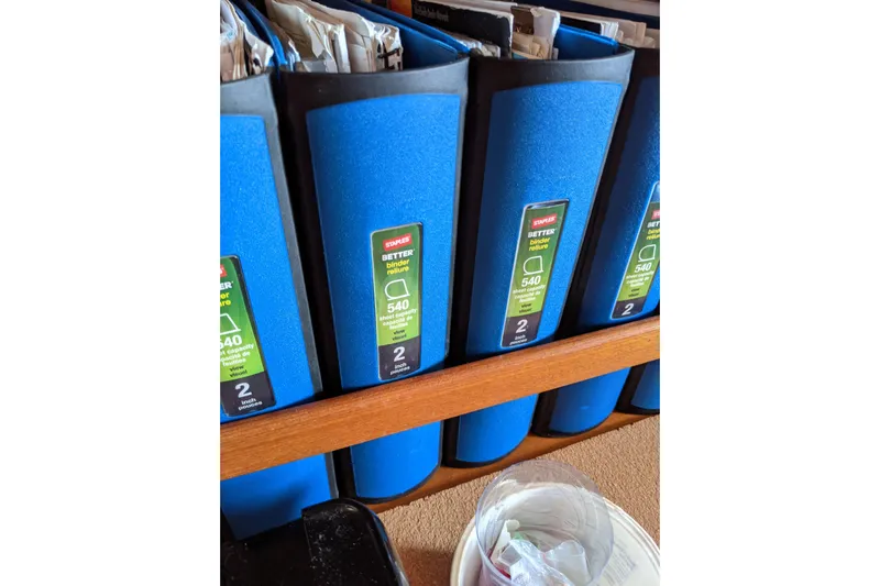 Mawe Yacht Photos Pics Blue binders labeled "Staples Better Binder" on a wooden shelf, Island Packet 440, 2006.