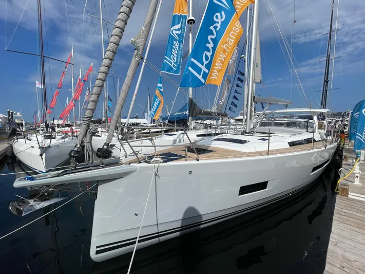 Uncorked Yacht Photos Pics 2023 Hanse 460 yacht docked at marina, showcasing sleek design and vibrant flags.