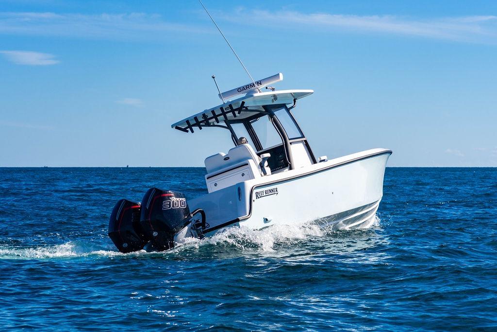 2026 Reef Runner 280 boat cruising on open sea with twin outboard engines.
