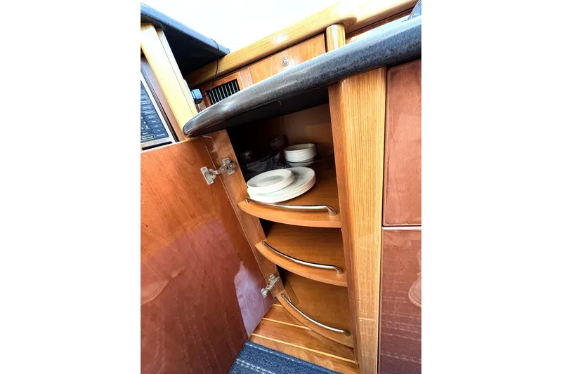 Pilot House Yacht Photos Pics Interior of 2003 Sealine F42/5 yacht showing wooden cabinet with plates.