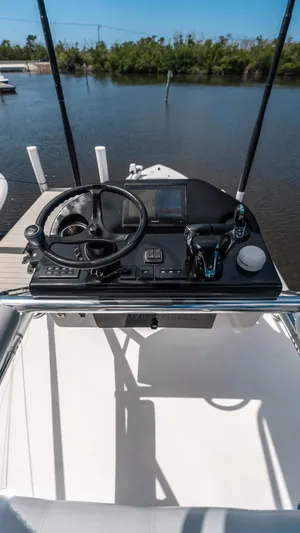  Yacht Photos Pics 2023 Contender 39 ST boat helm with steering wheel and controls, docked by a calm river.
