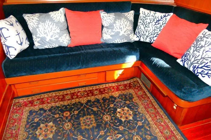 Avenir Yacht Photos Pics Cozy 1982 Ta Shing Mason 63 yacht interior with blue seating, coral-themed pillows, and ornate rug.