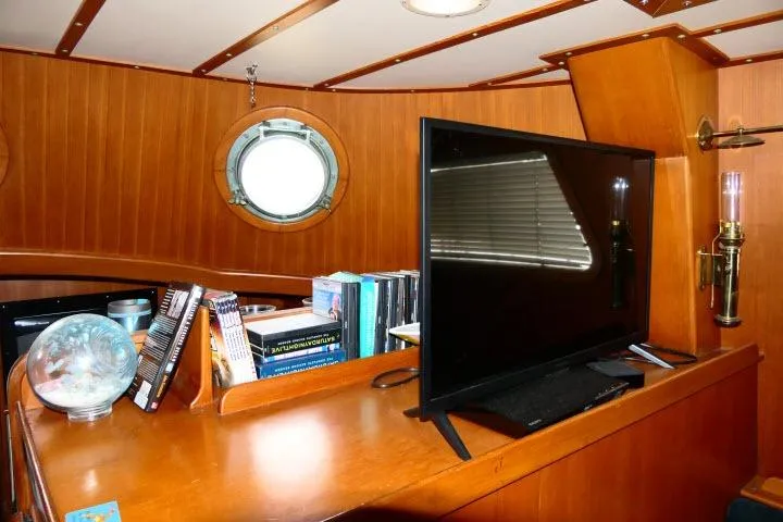 Avenir Yacht Photos Pics Interior of 1982 Ta Shing Mason 63 yacht with books, TV, and porthole window.