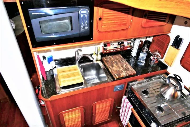 Avenir Yacht Photos Pics Compact kitchen in 1982 Ta Shing Mason 63 yacht with microwave, sink, and stove.