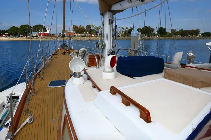 Avenir Yacht Photos Pics 1982 Ta Shing Mason 63 sailboat deck with wooden accents, docked by a calm shoreline.