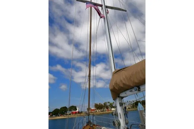 Avenir Yacht Photos Pics Sailboat mast of 1982 Ta Shing Mason 63 with American flag against cloudy sky.