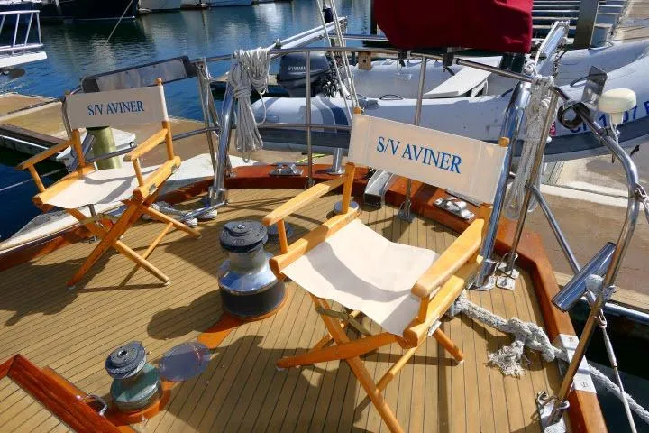 Avenir Yacht Photos Pics Deck of 1982 Ta Shing Mason 63 yacht with chairs labeled "S/V Aviner" at marina.