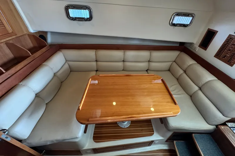  Yacht Photos Pics 2003 Mainship Pilot 34 interior with beige cushioned seating and wooden table.