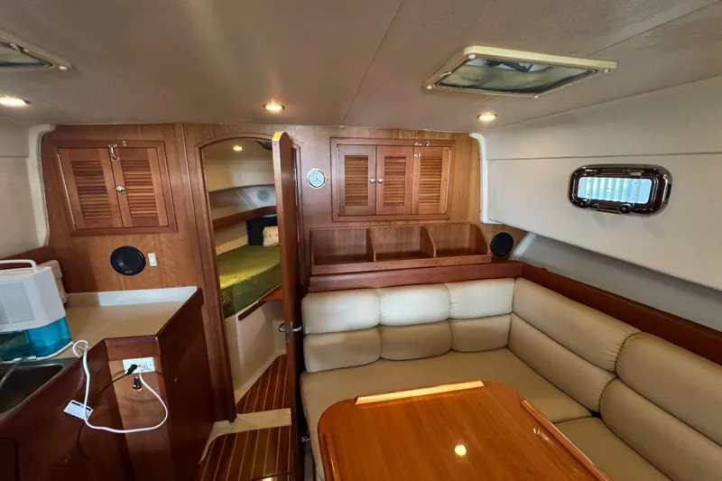  Yacht Photos Pics 2003 Mainship Pilot 34 interior with wood cabinetry, cozy seating, and a compact kitchenette.