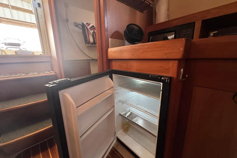  Yacht Photos Pics 2003 Mainship Pilot 34 interior with open mini fridge and wooden cabinetry.
