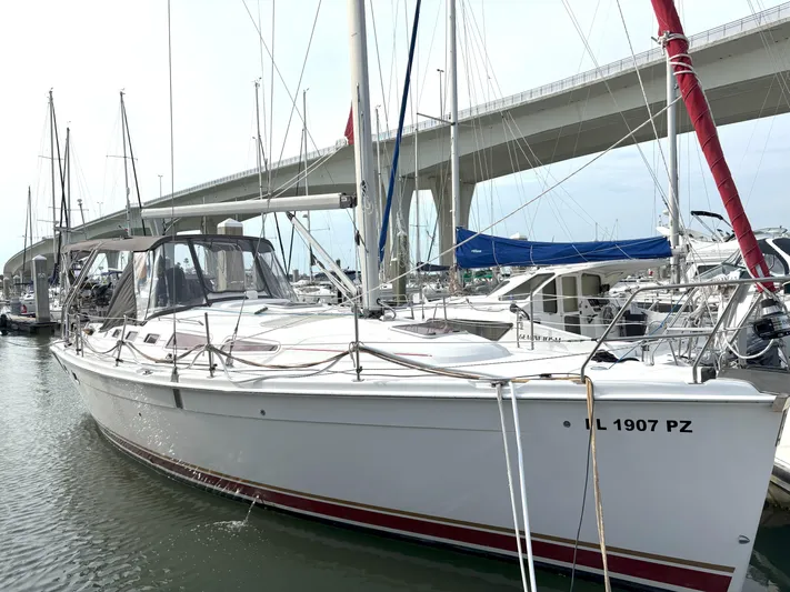 Bylgja Yacht Photos Pics 2005 Hunter 38 sailboat docked in marina, bridge in background, clear sky.