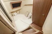 2024 Chris-Craft Launch 35GT cabin interior with cozy bedding and wooden accents.