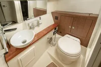 2024 Chris-Craft Launch 35GT bathroom with modern sink, toilet, and wooden cabinetry.