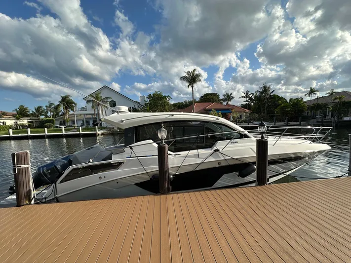 Olivia Yacht Photos Pics 2020 Four Winns Vista 355 Coupe docked by waterfront homes under a partly cloudy sky.