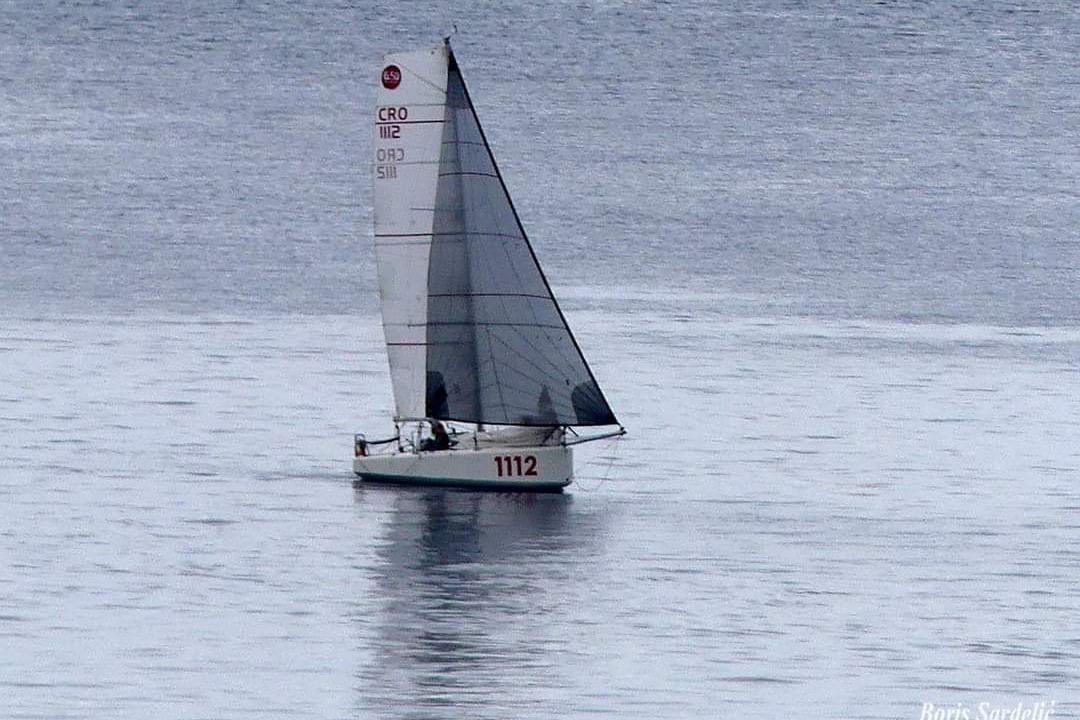 Sailboat CIMA Minitransat 650 (2024) on calm water, displaying sail number 1112.