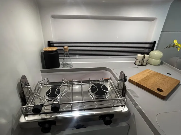  Yacht Photos Pics Compact kitchen in 2025 Beneteau First 30 yacht with stove and cutting board.