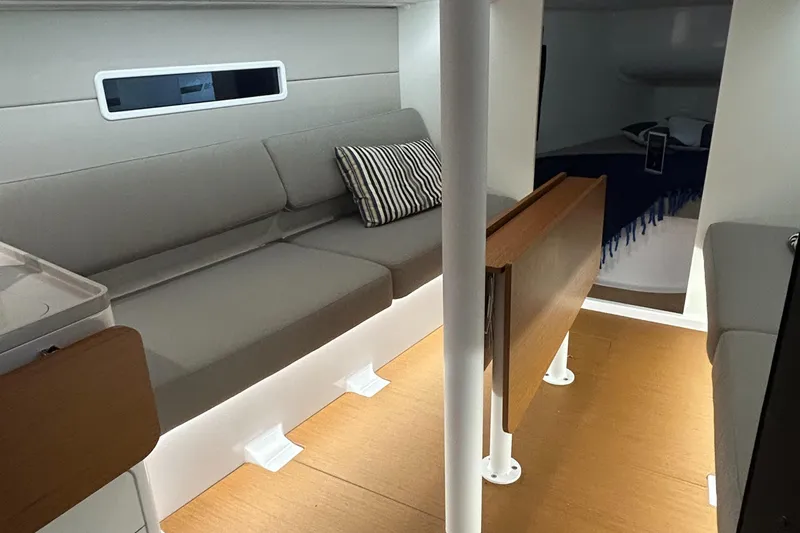  Yacht Photos Pics Interior of 2025 Beneteau First 30 sailboat with modern seating and wooden flooring.