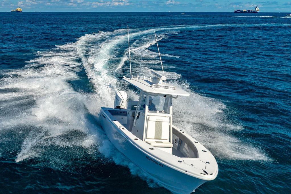 2026 Reef Runner 230 boat cruising on open ocean with wake trails.