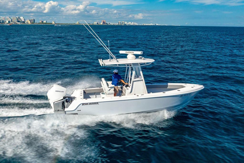 2026 Reef Runner 230 boat cruising on open ocean with city skyline in background.